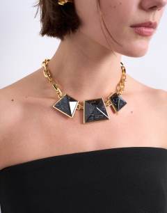 Model wearing Milo statement necklace in gold and black