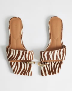 Model wearing Mina mule flat sandal with hardware hair on real leather zebra