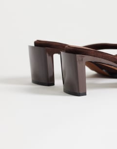 Model wearing Nadeem mid heel toe thong sandal with hardware in chocolate