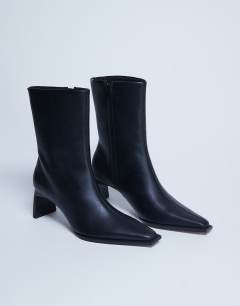 Model wearing Nadie chisel toe ankle boot in black
