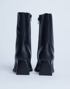 Model wearing Nadie chisel toe ankle boot in black