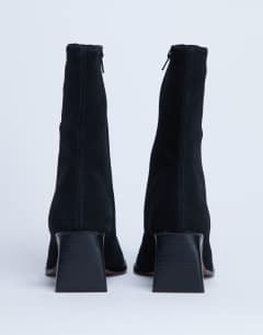Model wearing Nadie chisel toe heeled ankle boot in black suede