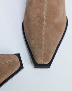 Model wearing Nadie real suede chisel toe ankle boot in beige