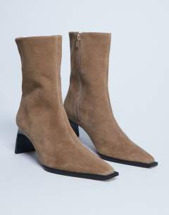 Model wearing Nadie real suede chisel toe ankle boot in beige