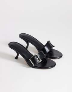 Model wearing Nadine mid heeled mule with buckle in black