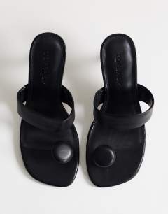 Model wearing Natalie toe thong angular mid heel sandal in black