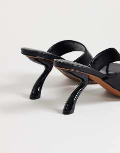 Model wearing Natalie toe thong angular mid heel sandal in black