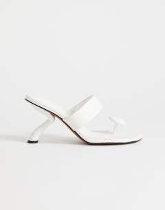 Model wearing Natalie toe thong angular mid heel sandal in white