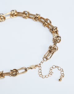 Model wearing Nicky waterproof stainless steal knot detailed necklace in gold