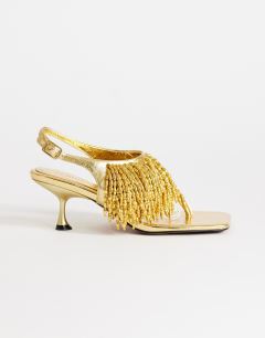 Model wearing Night beaded  toe thong heeled sandal in gold