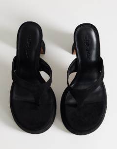 Model wearing Nima platform heeled toe thong sandal in black