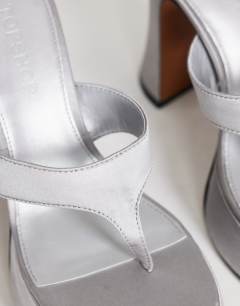 Model wearing Nima platform heeled toe thong sandal in grey satin