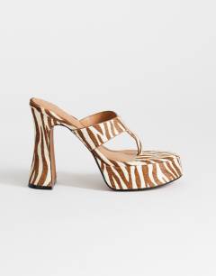 Model wearing Nima real leather with hair platform heeled toe thong sandal in zebra