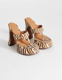 Model wearing Nima real leather with hair platform heeled toe thong sandal in zebra