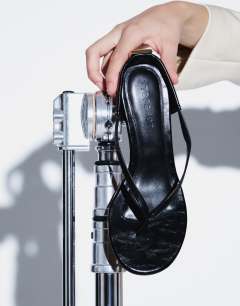 Model wearing Nix toe thong mid heel sandal with hardware in black