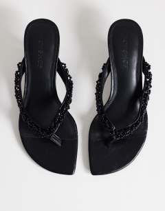 Model wearing Nolan beaded toe thong mid heel sandal in black
