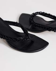 Model wearing Nolan beaded toe thong mid heel sandal in black