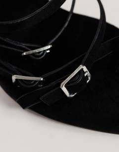 Model wearing Nori buckle detail heeled mule in black faux suede