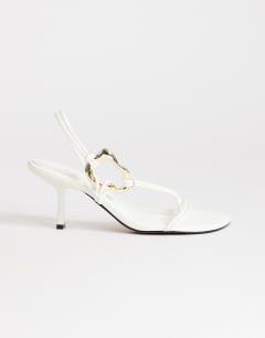 Model wearing Nova strappy mid heeled sandal with hardware in white