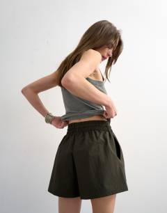 Model wearing Nylon runner short with insert ties in dark green