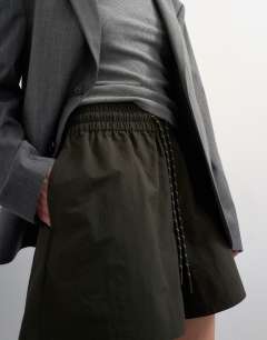 Model wearing Nylon runner short with insert ties in dark green