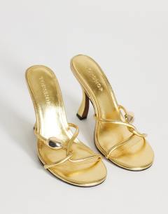 Model wearing Olivia strappy high heel sandal with ball detail in gold