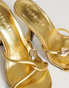 Model wearing Olivia strappy high heel sandal with ball detail in gold