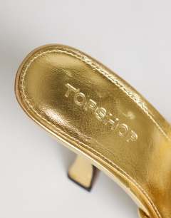 Model wearing Olivia strappy high heel sandal with ball detail in gold
