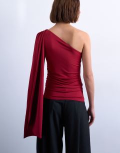 Model wearing One shoulder cape detail top in red