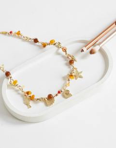 Model wearing Orla bead necklace with gold charms in orange multi