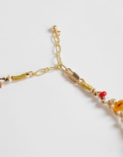 Model wearing Orla bead necklace with gold charms in orange multi