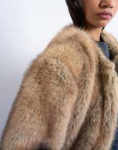 Model wearing Oversized faux fur collarless long coat in natural stripe in beige