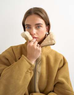 Model wearing Ovoid shearling jacket in tan