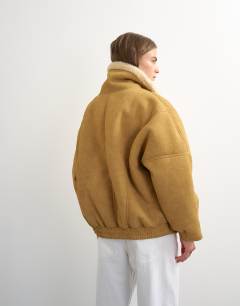 Model wearing Ovoid shearling jacket in tan