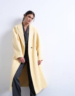 Model wearing Ovoid sleeve double breasted longline formal coat in buttermilk
