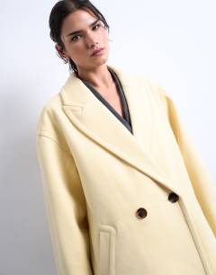 Model wearing Ovoid sleeve double breasted longline formal coat in buttermilk