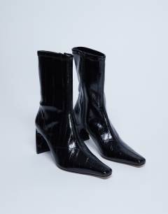 Model wearing Pearl point toe ankle boot in black eel