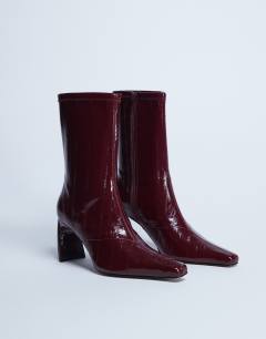 Model wearing Pearl point toe ankle boot in burgundy eel