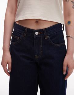 Model wearing Petite Cinch low rise relaxed jean in raw look indigo 