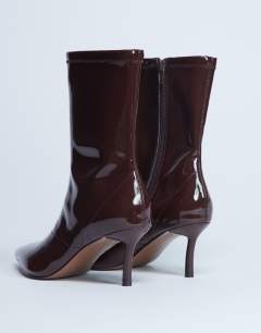 Model wearing Pippa point toe stretch ankle boot in patent chocolate