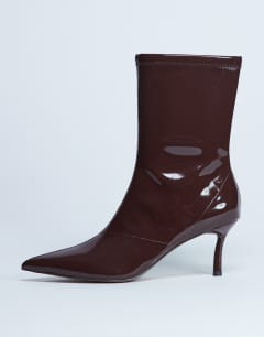 Model wearing Pippa point toe stretch ankle boot in patent chocolate
