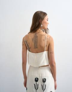 Model wearing Placement embroidery satin cami in cream