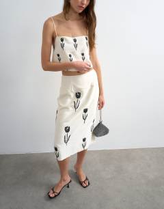 Model wearing Placement embroidery satin midi skirt in ecru