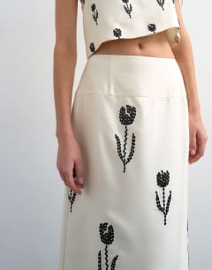 Model wearing Placement embroidery satin midi skirt in ecru