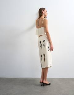 Model wearing Placement embroidery satin midi skirt in ecru