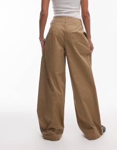 Model wearing Pleated wide leg tailored high waisted chino style trouser in sand