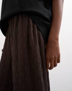 Model wearing Plisse jersey wide leg trousers in chocolate