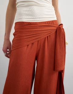 Model wearing Plisse wrap scarf detail trousers in rust