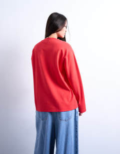Model wearing Premium interlock long sleeve skater tee in red