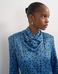 Model wearing Premium satin collapsed funnel shoulder pad mini dress in blue geo print